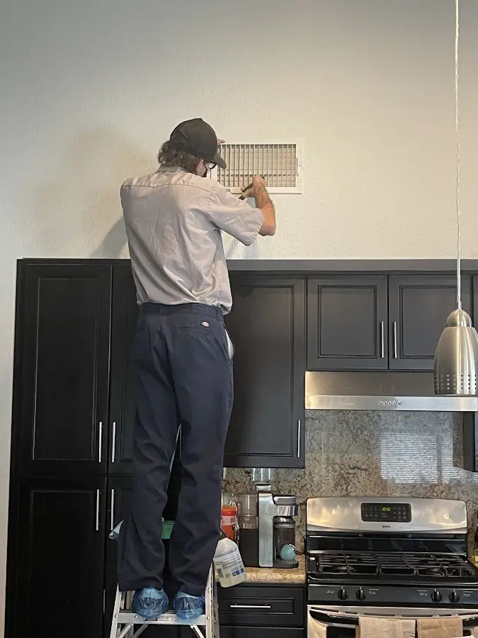 Technician inspecting an air vent during HVAC service in East Lake